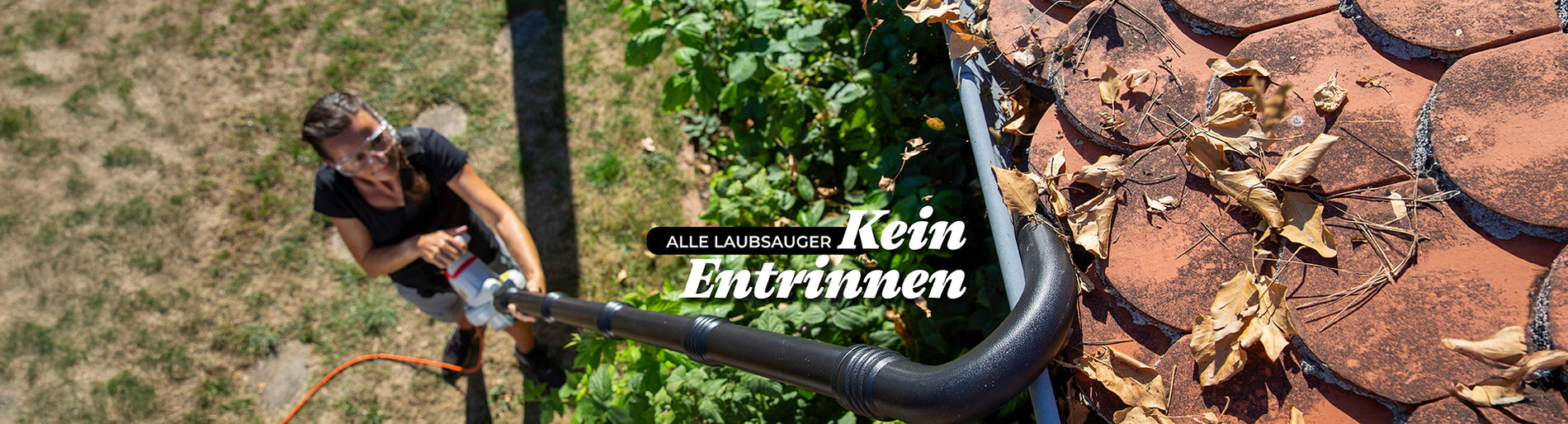 Frau reinigt mit einem Laubbläser eine Dachrinne